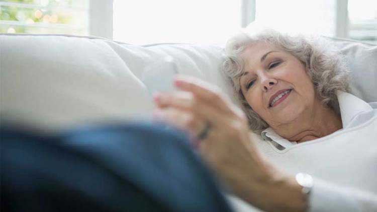Mujer mayor mirando su dispositivo portátil revisando su aplicación móvil de monitoreo de salud.