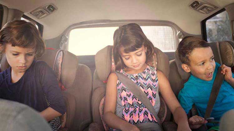 Niños sentados en el asiento trasero de un carro.