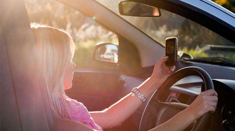 Una conductora adolescente enviando mensajes de texto en su teléfono mientras maneja.