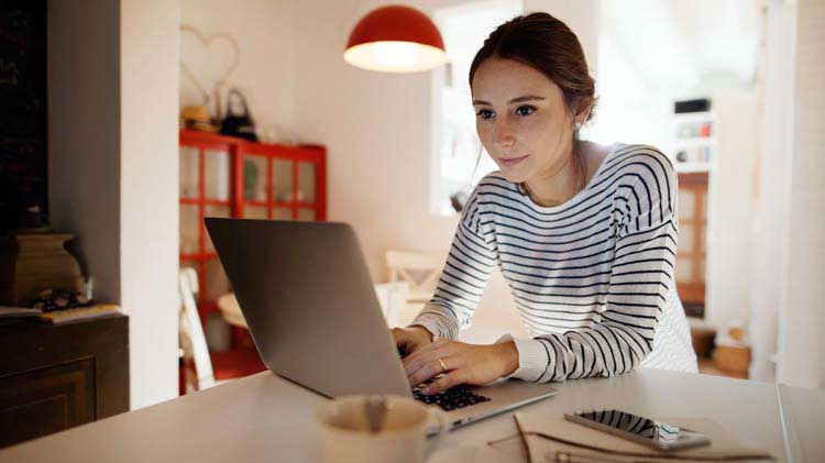 Una mujer joven controla su presupuesto en su computadora portátil.