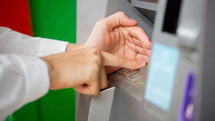 La mano de una persona ingresando su número PIN en un cajero automático.