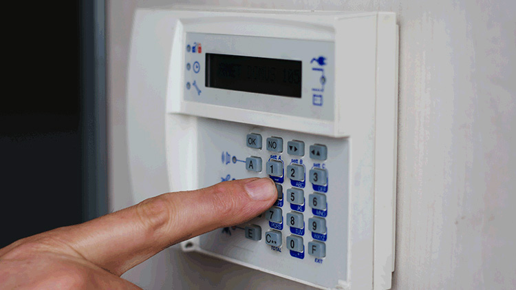 Persona introduciendo un código en el teclado de una caja fuerte del hogar.