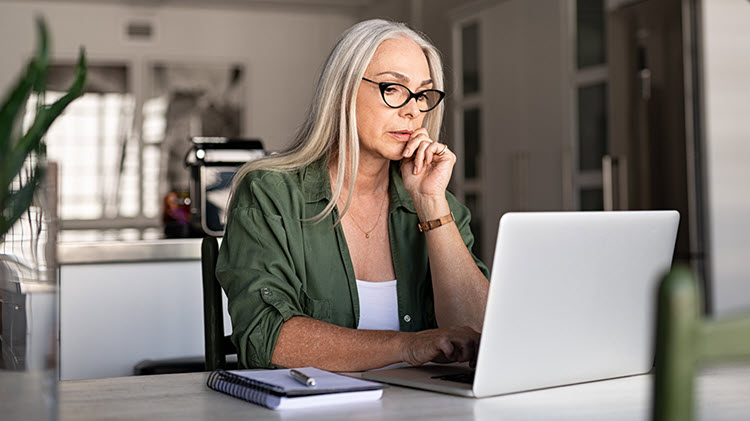 La mujer se sienta frente a la computadora portátil, revisando su plan de sucesión.