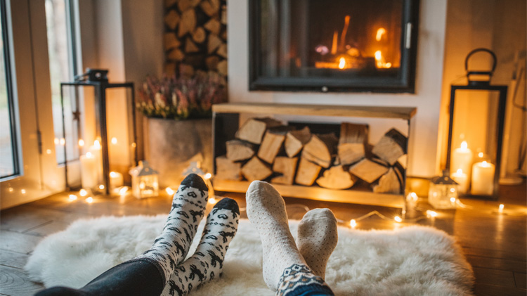 Una pareja en calcetines sentada con los pies en alto disfruta de su chimenea.