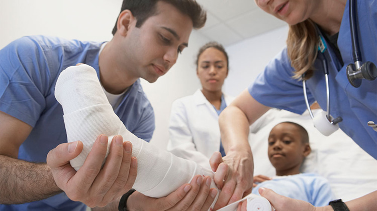 Médicos y enfermeros vendando el pie y la parte inferior de la pierna de un niño en un hospital.