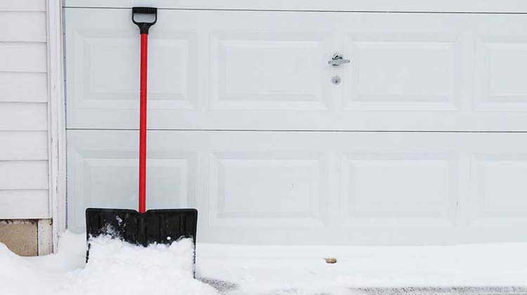 Pala de nieve junto a la puerta del garaje.