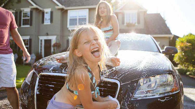 Una familia en casa lavando el carro que recientemente refinanciaron