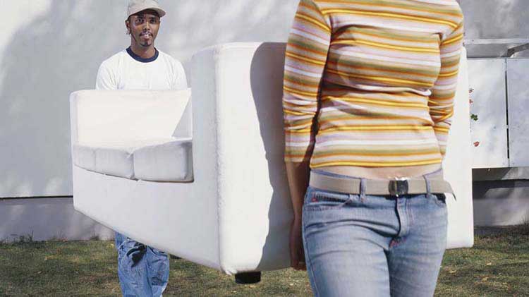 Dos personas cargando un sofá después de haber adquirido seguro para mudanzas.