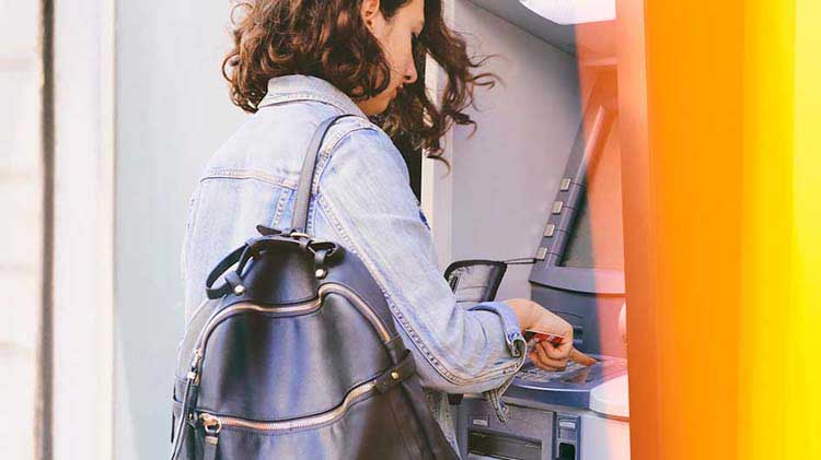 Una mujer tiene acceso los fondos de su cuenta de cheques usando un cajero automático.