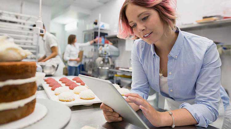 Propietario de panadería que revisa los planes de jubilación de pequeñas empresas en un iPad.