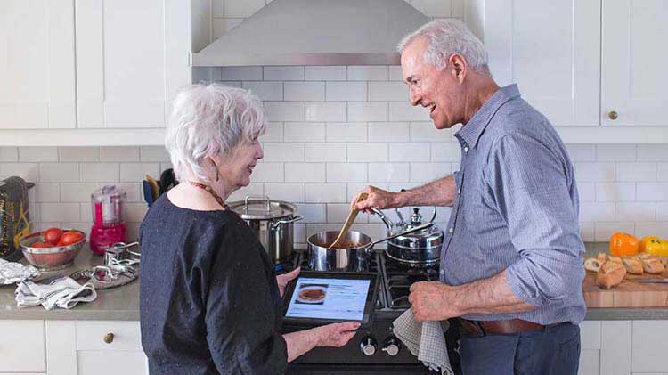 Una pareja veterana conversa sobre su jubilación mientras repasan información en una tableta.