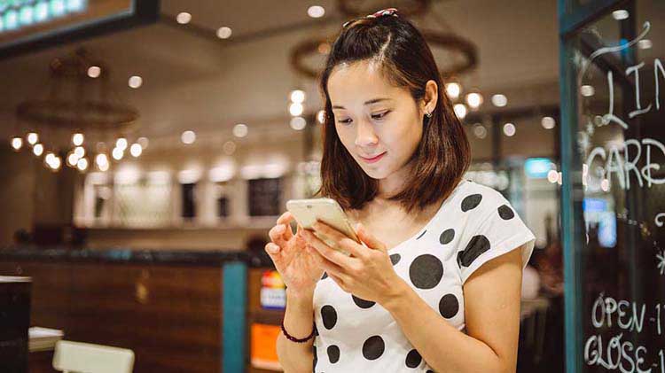 Una mujer mirando su teléfono celular inteligente y accediendo a sus archivos almacenados en la nube.