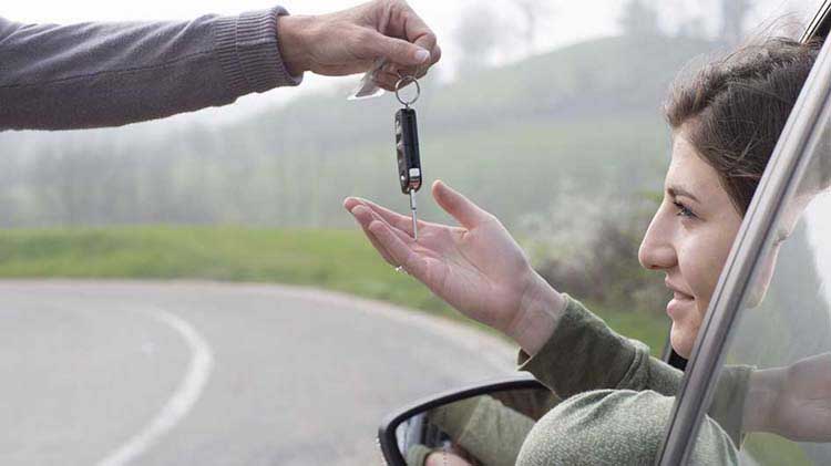 Mano de los padres dejando caer las llaves del automóvil en la mano del conductor adolescente.