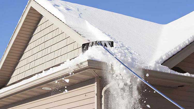 Una herramienta de nieve es usada para limpiar nieve de un techo.