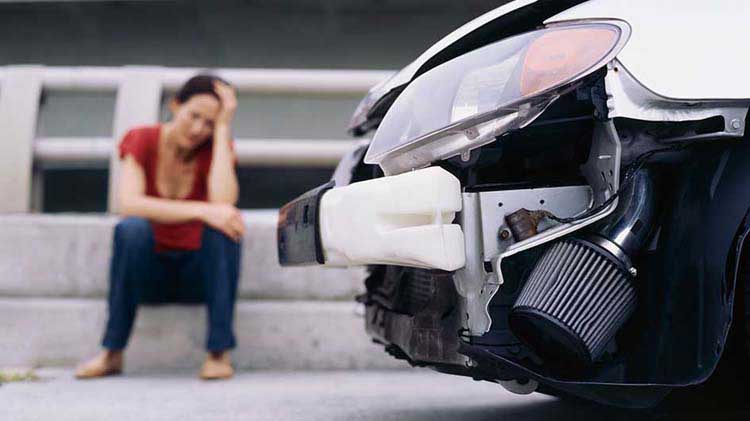 Una mujer está molesta cerca de su carro después de un accidente.