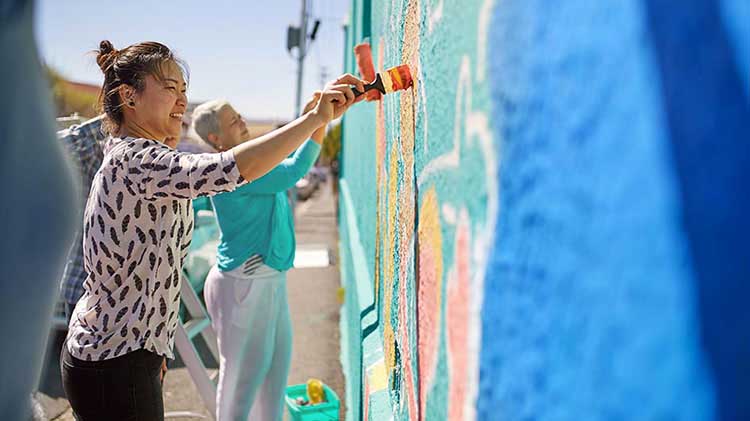 Mujeres pintando una pared mientras están de vacaciones voluntarias.