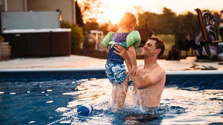 Un padre carga a un niño en la piscina.
