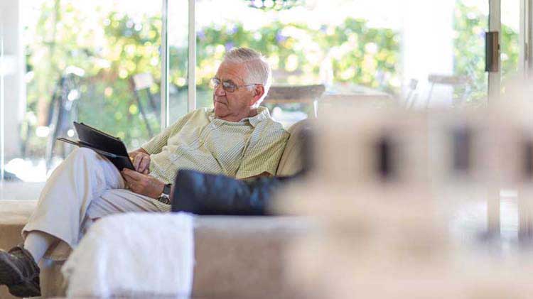 Un anciano en su sofá investigando Medicare en línea.