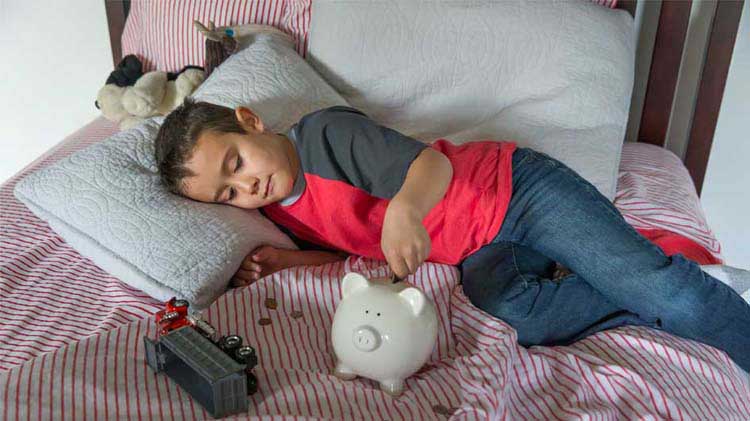 Boy on bed with his piggy bank.