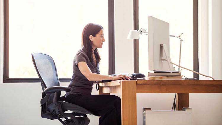 Mujer sentada en un escritorio frente a una computadora.