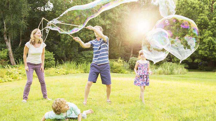 Familia juega en un patio con burbujas gigantes de jabón