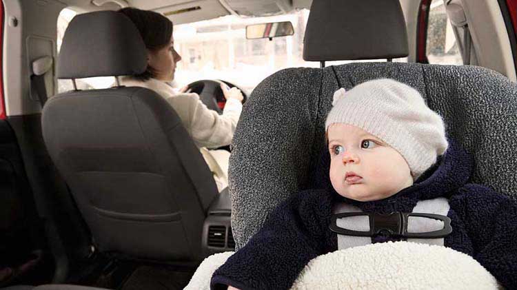 Bebé en asiento infantil ubicado en el asiento trasero del carro