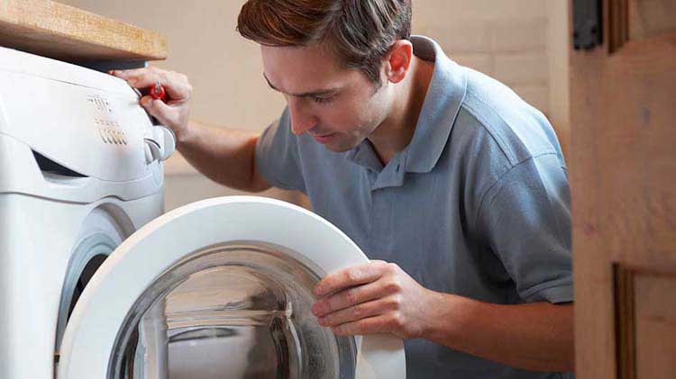 Un hombre mirando el interior de una lavadora.