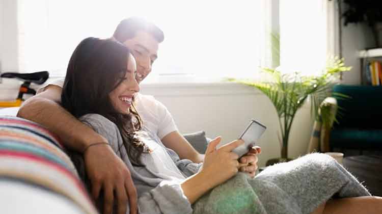 Una pareja sentada en su sofá con una tableta pensando en refinanciar un préstamo