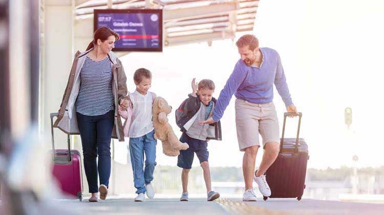 Mamá, papá y dos hijos de viaje en el aeropuerto con su equipaje.