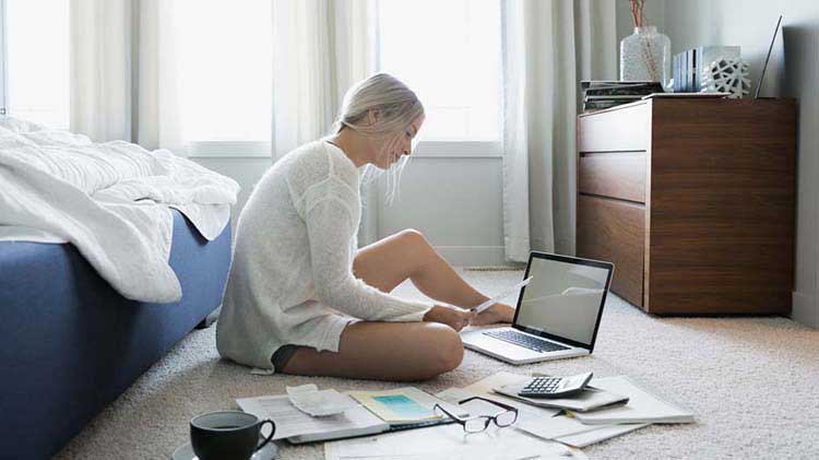 La mujer busca en el papeleo y en su computadora portátil un nuevo apartamento.