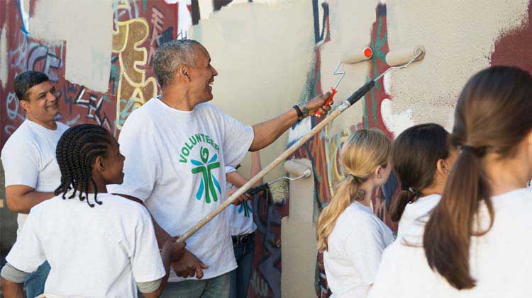 Un grupo de personas pintando una pared para quitarle graffiti.