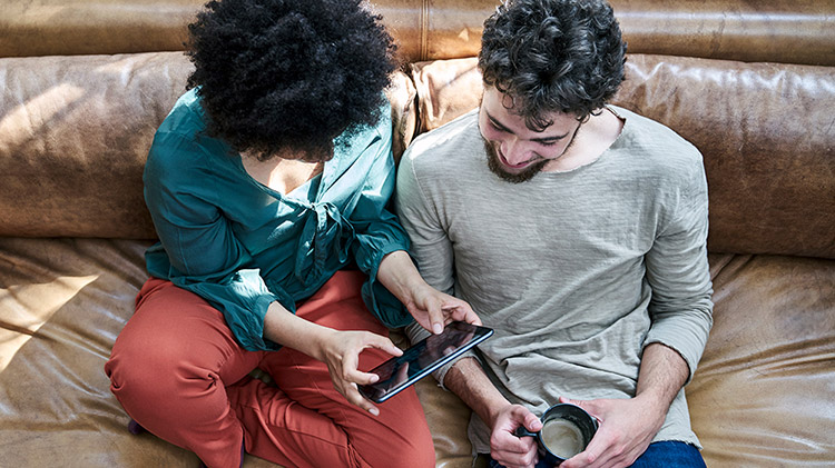 Una pareja usa una tableta para revisar sus ahorros.