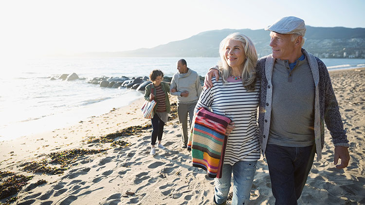 Una pareja jubilada camina en la playa, disfrutando un viaje para celebrar el hito de haberse jubilado