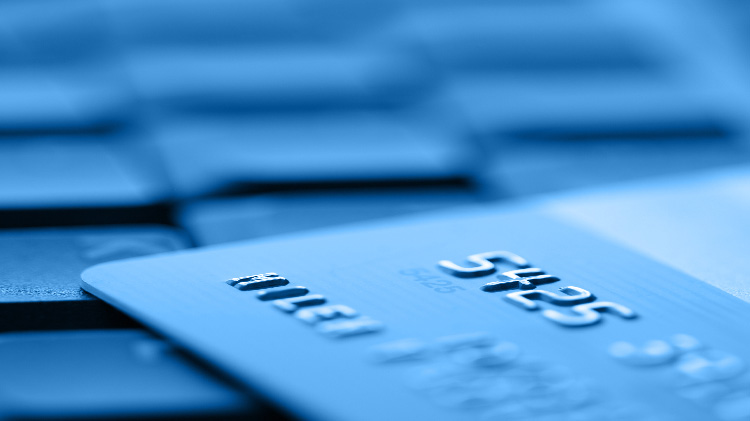 Una persona en una computadora portátil pagando por un servicio de monitoreo crediticio con una tarjeta de crédito.