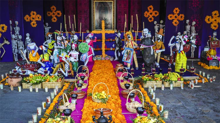 Altar del Día de los Muertos con flores, catrines y otras ofrendas.