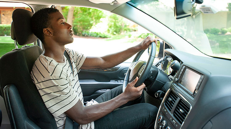Joven con cinturón de seguridad maneja su carro y practica el manejo preventivo