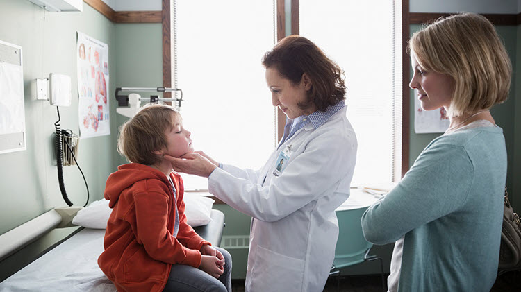 Doctora examinando a un niño pequeño con la madre observando