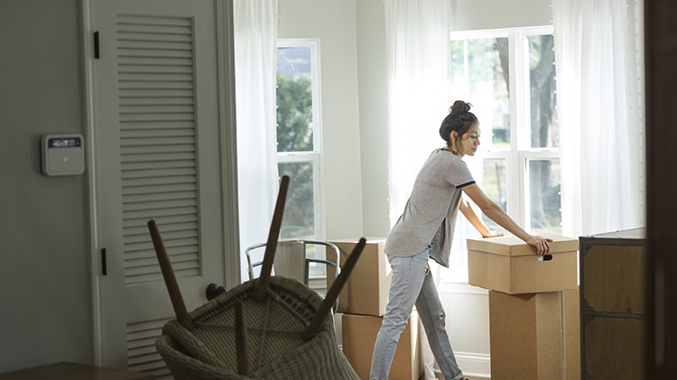 Una mujer se apoya en una caja de embalaje mientras empaca para mudarse después de su divorcio