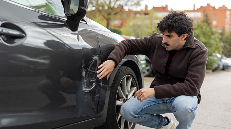 Un joven revisa los daños sufridos por su vehículo tras un accidente de carro.