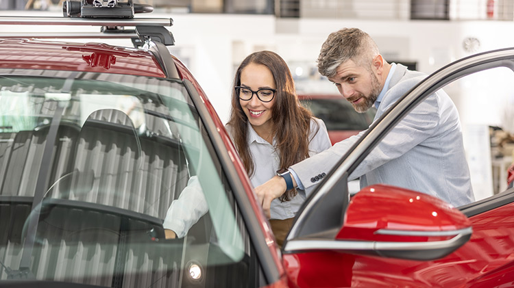 Una pareja pensando en comprar un carro rojo