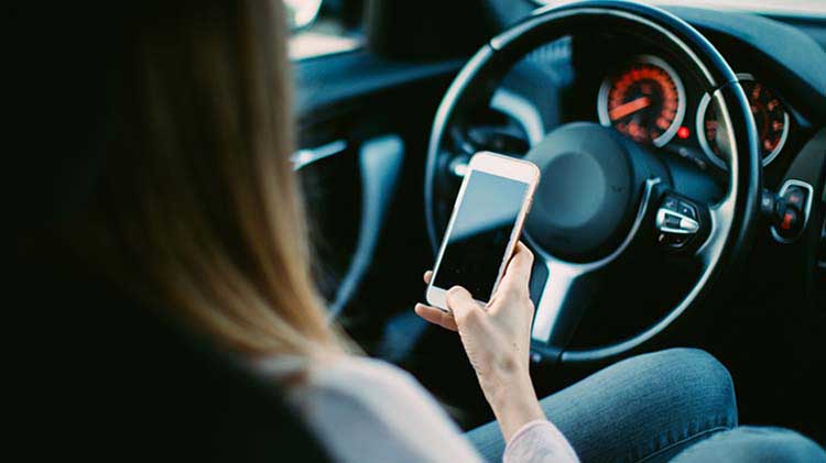 Mujer conduciendo distraída con el celular.