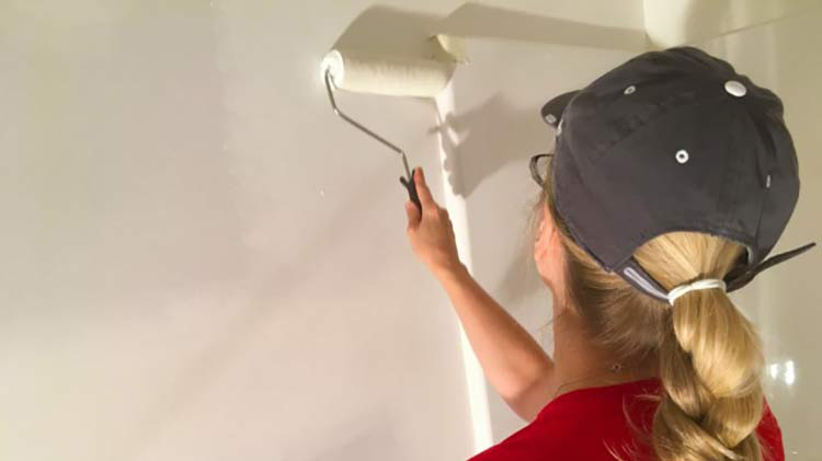 Mujer con camisa roja pintando una pared durante el mantenimiento del hogar.