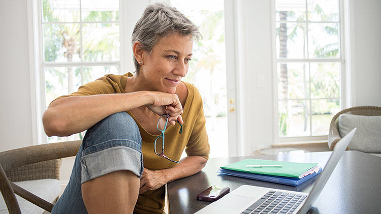Mujer mirando una computadora portátil y pensando en un plan de jubilación.