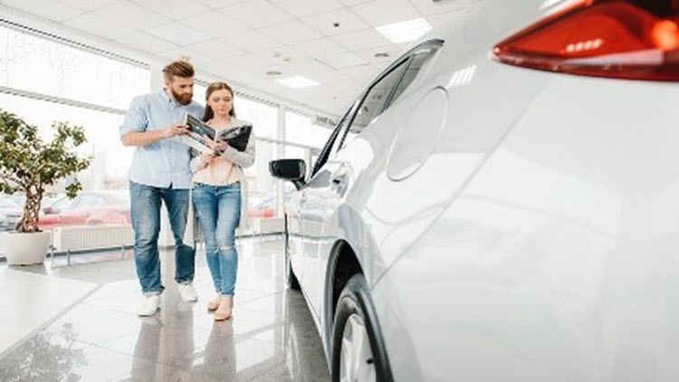 Una pareja en un concesionario comprando un carro y decidiendo el plazo del préstamo para carros.