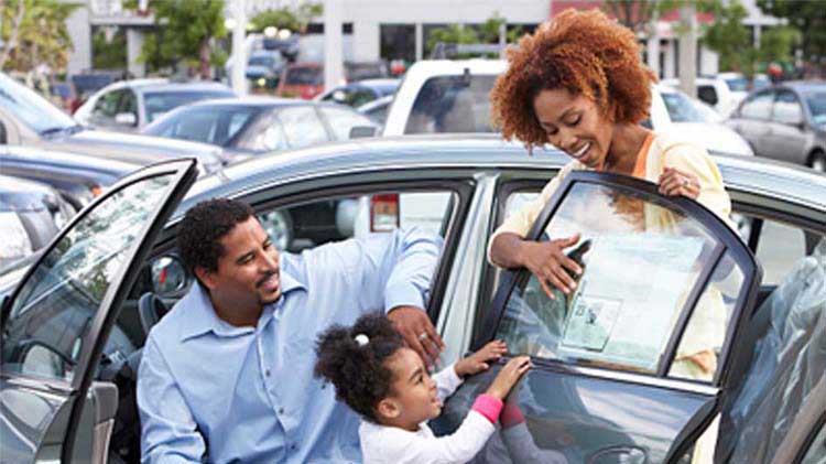Una familia inspecciona un carro usado en un concesionario.
