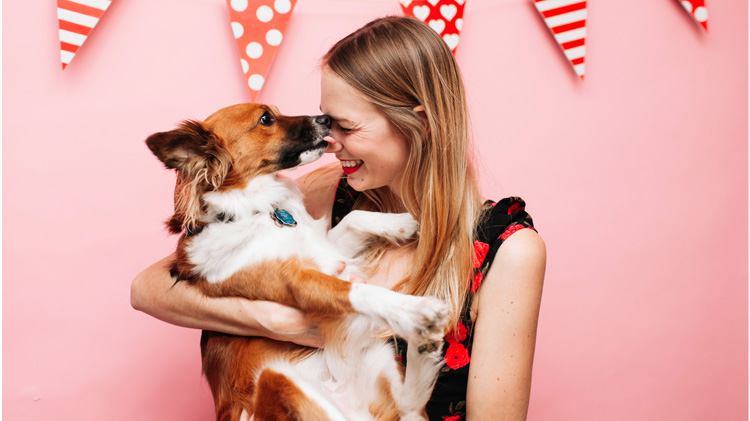 Mujer recibe besos de su mascota en el día del amor y la amistad.