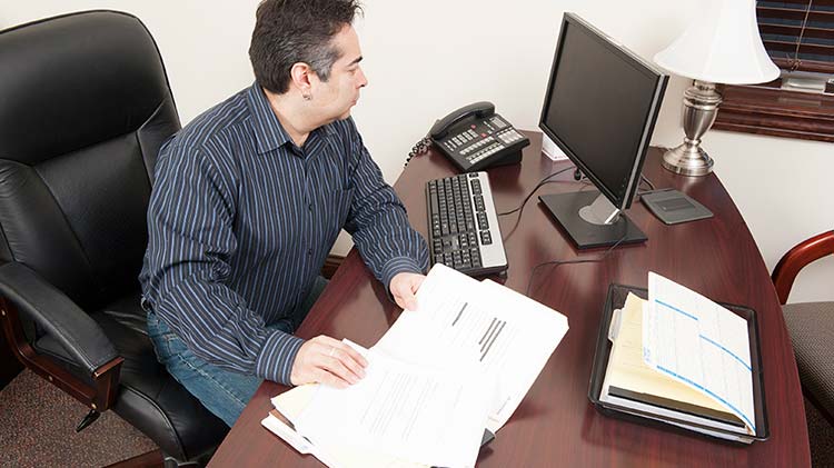 El dueño de una pequeña empresa se sienta en su escritorio trabajando en su inventario