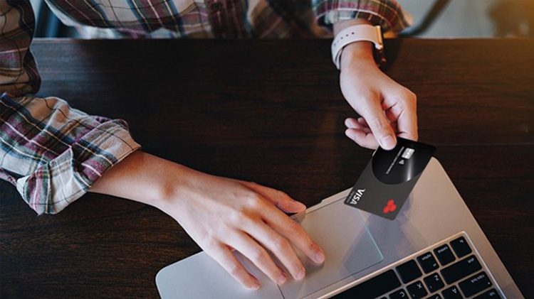 Persona usando el computador portátil para hacer una compra en línea con una tarjeta de crédito.