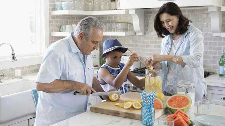 Una familia corta fruta en la cocina.