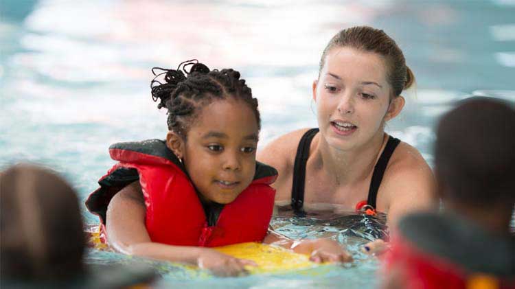 Una niña pequeña tomando clases de natación.
